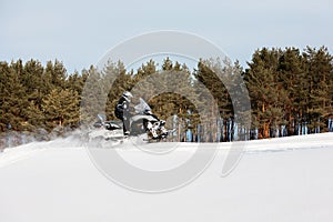 In deep powder snowdrift snowmobile rider driving fast