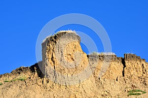 Deep sandy cliff on the background of blue sky.