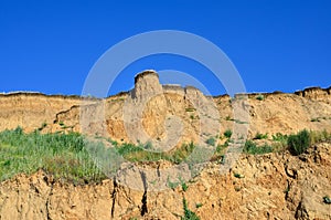 Deep sandy cliff on the background of blue sky.