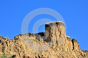 Deep sandy cliff on the background of blue sky.