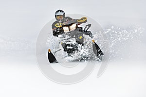 In deep snowdrift snowmobile rider make fast turn. Riding with fun in deep snow powder during backcountry tour. Extreme sport