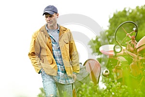 Deep in thought. a worried farmer walking away from his tractor in a field.