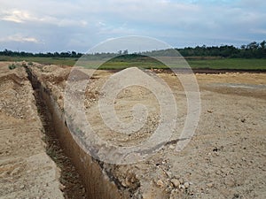 Deep trench cut in the dirt at construction site