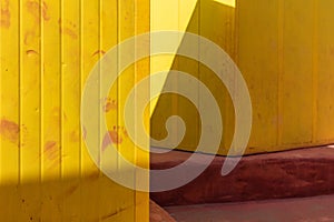 Deep yellow painted beach huts, on sunny but moody day. Blue sky, white clouds, seaside holiday architecture.