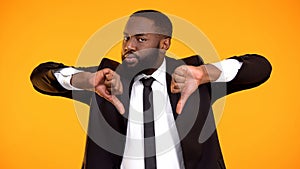 Deeply dissatisfied black man showing double thumbs-down, poor quality service