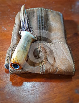a deer antler smoking pipe on a light brown leather wallet on a brown wooden table