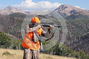 Deer hunter aiming rifle in rugged mountains photo