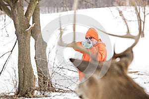 Deer hunter taking aim at a whitetail deer