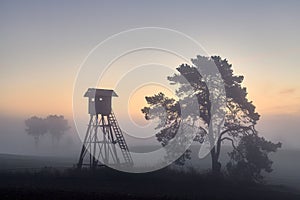 Deer hunting tower on a field in Autumn at dawn