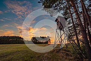 Deer stand tree stand beside field and forest at sunset light, Czech republic