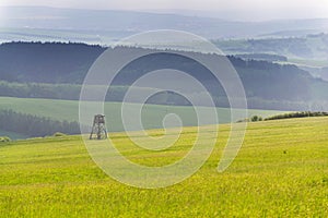 Deer stand, wooden hunters high seat hide on field, summer day, cloudy dramatic sky