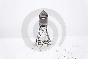 Deer stand, wooden hunters high seat hide on snow covered field, winter day