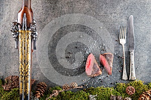 Deer or venison steak with antique long gun, cutlery and ingredients like sea salt and pepper, food background for restaurant or h