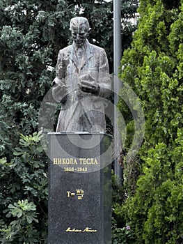 Defaced granite stone statue of Tesla in outdoor park in Belgrade, Serbia.