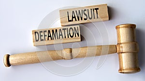 DEFAMATION LAWSUIT - words on wooden blocks on a white background with a judge\'s gavel photo