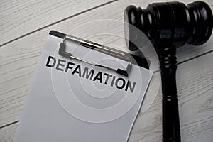 Defamation text write on a paperwork and gavel isolated on office desk