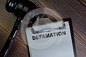 Defamation write on a paperwork isolated on Wooden Table photo