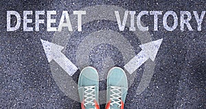 Defeat and victory as different choices in life - pictured as words Defeat, victory on a road to symbolize making decision and