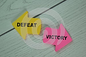 Defeat or Victory write on sticky notes isolated on Wooden Table