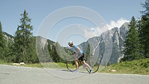 Defeated by the steep mountain road, pro cyclist walks along his road bicycle.