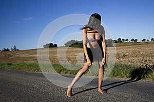 Defeated woman walking barefoot on a road.