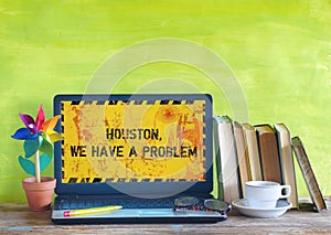 Defect laptop computer in home office, displaying message Houston We Have A Problem