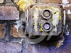 Defective old power switch in a fuse box made of rotten plastic on a brick wall