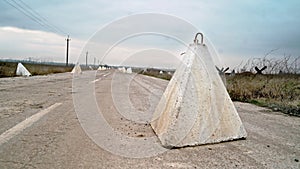 Defensive war concrete structures on the road. Anti-tank hedgehogs