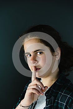 Defiant teenager with finger on lips.