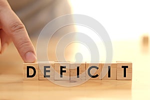 Deficit writing on wooden cube blocks, word text typography arrange on wood table