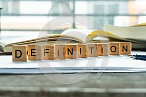 Definition print wording on wood block. on white notebook and office equipment.