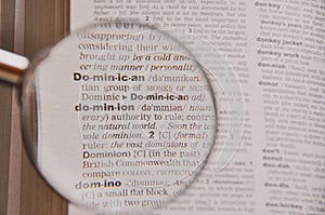 The definition of the word Dominion in a dictionary, under magnifying glass, translator and language concept