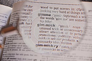 The definition of the word Gimmick in a dictionary, under magnifying glass, translator and language concept