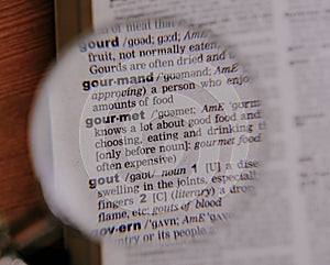 The definition of the word Gourmet in a dictionary, under magnifying glass, translator and language concept