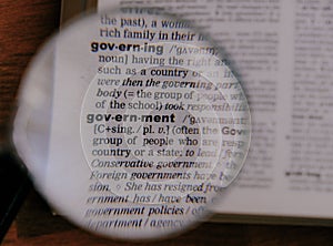 The definition of the word Government in a dictionary, under magnifying glass, translator and language concept