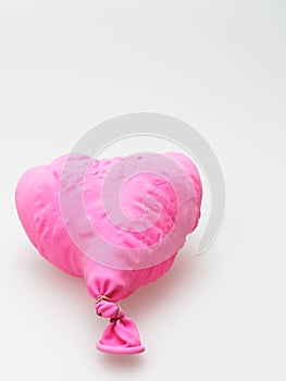 Deflate heart shape balloon in pink color isolated on white background