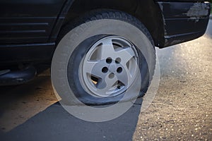 A deflated car wheel. Punctured car wheel on the street.