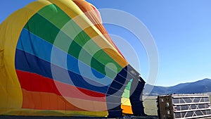 Deflated rainbow air balloon with clear blue sky in background