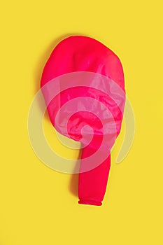 Deflated red balloon on a yellow background