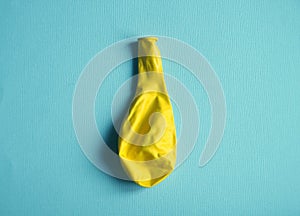 Deflated yellow balloon on blue background