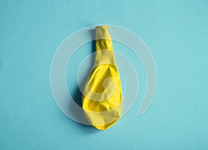 Deflated yellow balloon on blue background photo