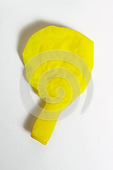 Deflated yellow balloon on a white isolated background