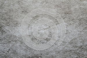 Defocus grey spunbond non-woven geotextile close-up macro. Small spots. Dirtied texture. Design, background, backdrop. Out of