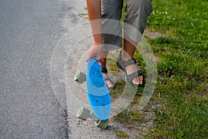 Defocus Little boy holding a penny skateboard. Young kid riding in the park on a skateboard. Child learns to ride a blue