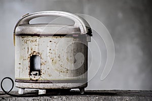 Defocus of old white electric rice cooker Was set on the edge of the cement wall, Old electric rice cooker rusty and has expired