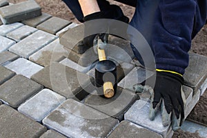 Defocus paver master. Man lays paving stones in layers. Garden brick pathway paving by professional paver worker. Hands