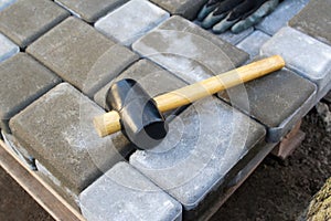 Defocus paving hammer. Stack of paving stones. Garden brick pathway paving by professional paver worker. Laying gray