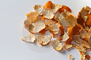 Defocus peels of orange and tangerine on a white background. Many small pieces of dried peel of mandarin. Orange bright