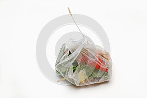 DEFOCUS. Plastic packaging. Red and green plants flowers in a plastic bag on a white background. A dry blade of grass