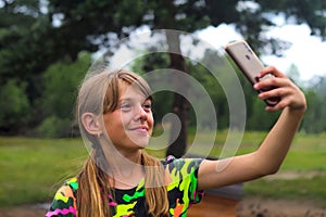 Defocus Selfies A ten year old girl poses and takes a selfie by hand Charming teen girl in summer standing on the yard